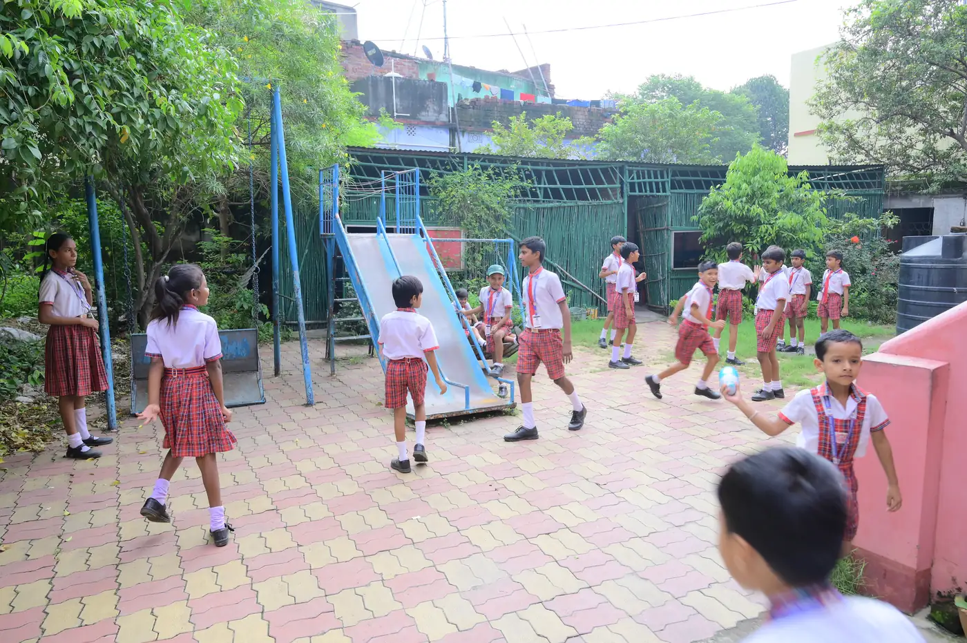 Children playing in the Kiddies Campus outdoor play area with slides